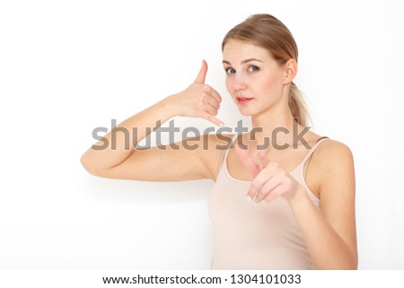Portrait of happy young woman. Call me back please. Makes phone sign, indicates with index finger directly at camera, wants to speak with someone via cell phone.