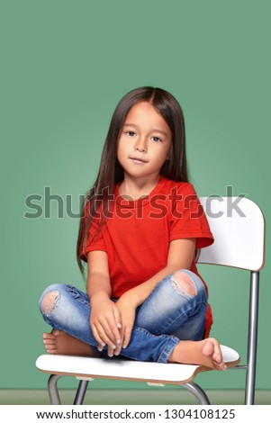 little girl wearing red t-short and posing on chair