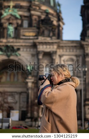 Outdoor lifestyle portrait of pretty young woman. Girl having fun in the city in Europe with camera. Travel photo of photographer. Making pictures