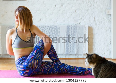 Young attractive yogi woman practicing yoga, stretching in Bound Half lord of the fishes pose (Baddha Ardha Matsyendrasana), working out, wearing blue sportswear, cool urban style, full length.
