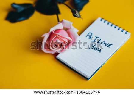 "PS.: I love you" note, rose with note on yellow isolated background. Valentine's day concept . Love message.