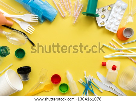 White single-use plastic and other plastic items on a yellow background. The concept of choice without plastic or environmental problems. Royalty-Free Stock Photo #1304161078