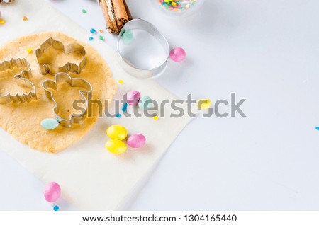  dough and indredients, cuts for cookies Easter and colored sugar décor for baking on a white background, The process of making fragrant Easter cookies, series photo, top view, flat lay, copy space 