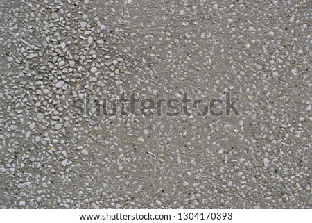 Grey gravel or crushed stone material decored on cement wall. Closeup of gray texture background.