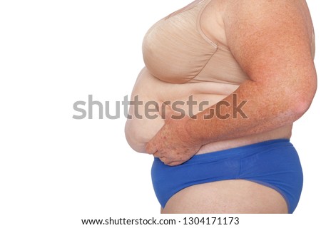 Menopausal woman with weight gain after brachioplasty, panniculectomy, abdominoplasty and mummy makeover. Side view hands holding excess abdominal weight, copy space left. Makeover inspiration. Royalty-Free Stock Photo #1304171173