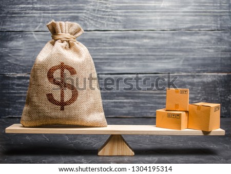 A bag of money and a bunch of boxes on the scales. Conceptual trade balance between countries and unions, trade and exchange of goods. Economic relations between subjects, the global economic model. Royalty-Free Stock Photo #1304195314
