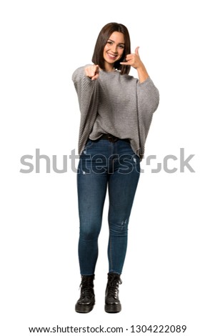 A full-length shot of a Young woman making phone gesture and pointing front over isolated white background
