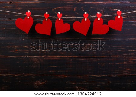 Red hearts on rope with clothespins, on black wooden background. Place for text, copy space.