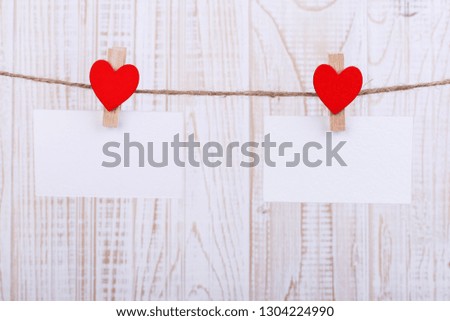 Handmade red felt hearts and white paper hanging on rope with clothespins. Concept, banner, copy space, form.