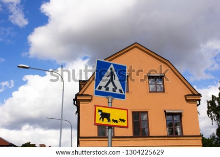 Cityscape with a facade of an old house and a pedestrian crossing sign for people and cats