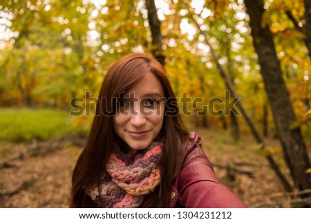 Selfie of a young woman with reddish hair in an autumnal forest of yellow and ocher colors in Montanchez, Caceres, Extremadura
