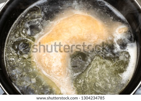 boiled chicken in a pot broth close-up with blurred background and front