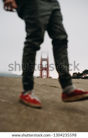 Man walking on a platform with the Golden Gate in the background.