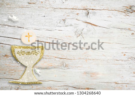 First Holy Communion invitations, silver and gold chalice and dove on white wooden background with empty space for text and photos Royalty-Free Stock Photo #1304268640