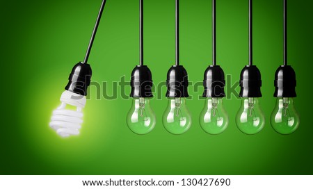 Perpetual motion with light bulbs and energy saver bulb. Idea concept on green background. Royalty-Free Stock Photo #130427690