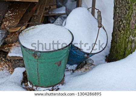 two old metal buckets with white snow on a tree street