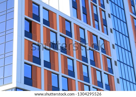 Close up of orange and red cladding around windows of a block of student accommodation in an English city.  Royalty-Free Stock Photo #1304295526