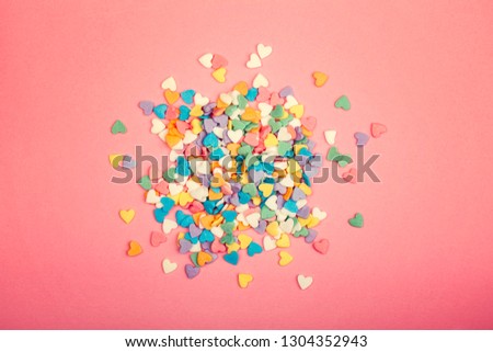 Happy Valentine Day. Beautiful card wallpaper with pile of colorful hearts candies in centre on pink coral background. Gradient toned backdrop. Concept of love  February holiday. 