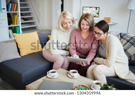 Portrait of three modern women browsing internet using digital tablet together, copy space