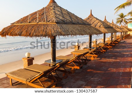 Seashore, sand beach with umbrellas and sunbeds on background of the sea and sky at dawn