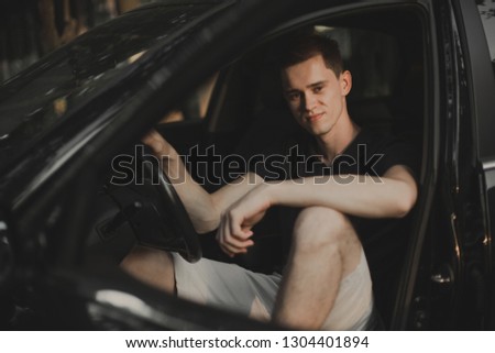 Young man sitting in his car.
