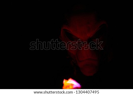 alien face lite up by fire with black background              