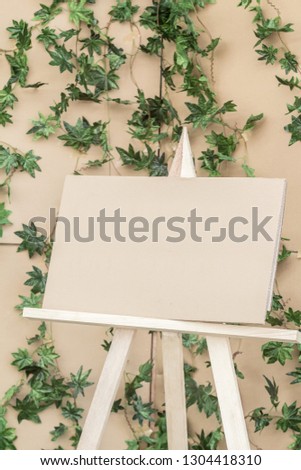 blank carton label on easel on carton and ivy plant background.