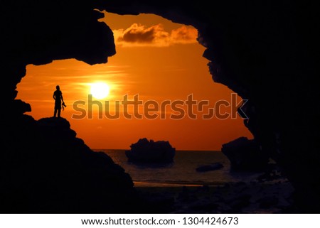 Man standing on the rock by the sea at red sky sunset.Silhouette background concept.