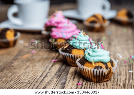 Chocolate cupcake with colored pink and green cream on wood table