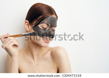 woman applies cosmetic mask with face brush