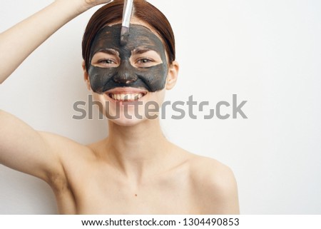 smiling woman applies cosmetic mask on face