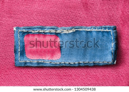 Blank clothes label on pink textile background closeup