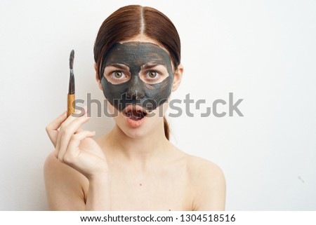 woman surprised holding a brush on the face cosmetic clay mask