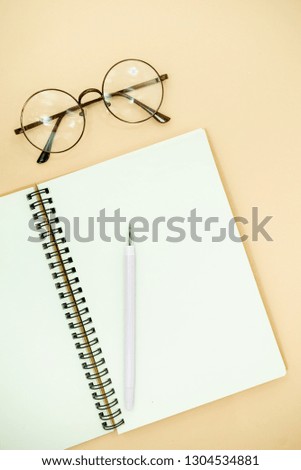 Stationary concept, Flat Lay top view Photo of pencils, glasses and notepad  on a beige abstract background with copy space, minimal style. Flat lay blog mock-up and a plant . 