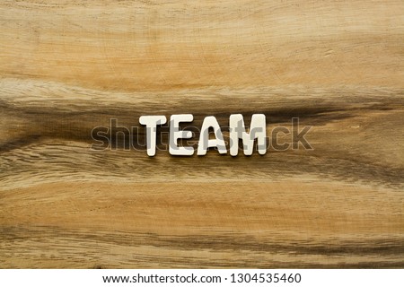 Plywood alphabets on acacia wooden texture background concept. The word "TEAM" on wood pattern backdrop.