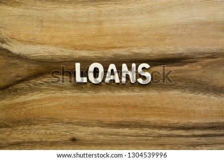Plywood alphabets on acacia wooden texture background concept. The word "LOANS" on wood pattern backdrop.