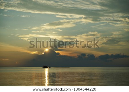 sunset over on a ocean, accentuated Very clear and bright perspective with clouds layers that accentuate the horizon, while several sun rays penetrates the clouds                              