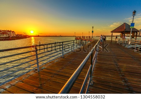 Scenic sunset on San Diego Bay from the old wooden pier in Coronado Island, California. People and tourists fishing and walking and enjoying the view of the San Diego skyline downtown waterfront.