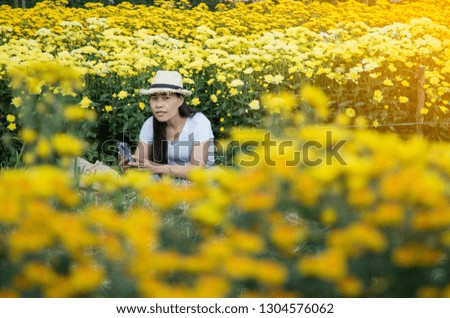 Asian woman using smartphone selfie in yellow flowers garden
