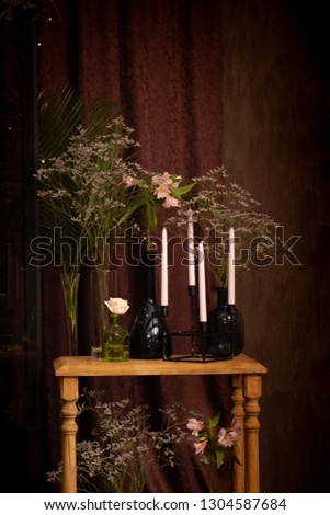 Background for design in dark colors, photo zone with an armchair, a table with flowers and candles.