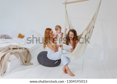 Mom with her little son and daughter sitting on a pouf and watching a cartoon / mom and children spending time with children / copy space