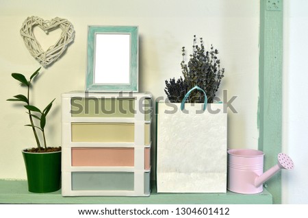 Watering can, lavender in paper bag, home plants and picture frame on shelf. Loft life style home decoration on vintage shelf, mockup background