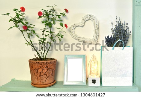 Paper bag with lavender flowers, rose plant in pot, picture frame on wooden shelf. Loft life style home decoration on vintage shelf, mockup background