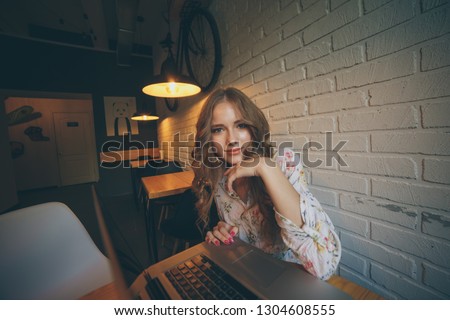 Picture of pretty young curly hail girl with laptop smiling and sitting in a cafe