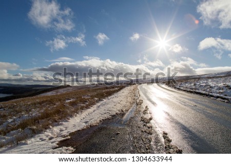 Sunburst over a snowy and icy road in the Brecon Beacons National Park. The A4059 is the route to Pen y Fan on the A470 - UK 