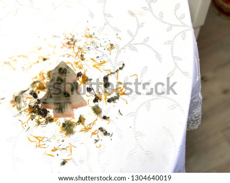 transparent handmade soap in the shape of Christmas trees with the use of herbs on the white background of the tablecloth