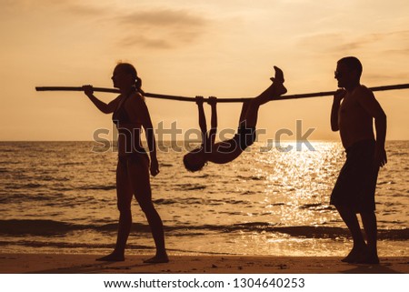 Happy family playing on the beach at the sunset time. People having fun outdoors. Concept of summer vacation and friendly family.