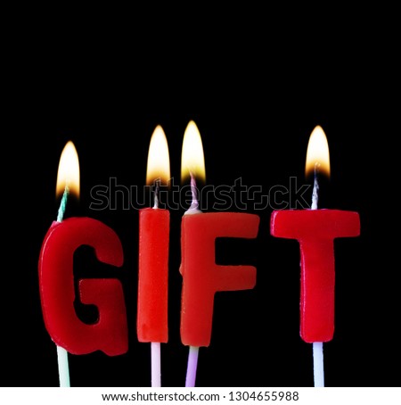 Gift spellt out in red birthday candles against a black background