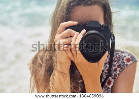 young girl taking pictures on camera in a summer on the beach. Girl holding a camera.