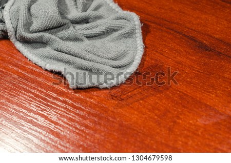 Grey wet rag on the dirty wooden desk. Cleaning the house or doing household chores concept.
